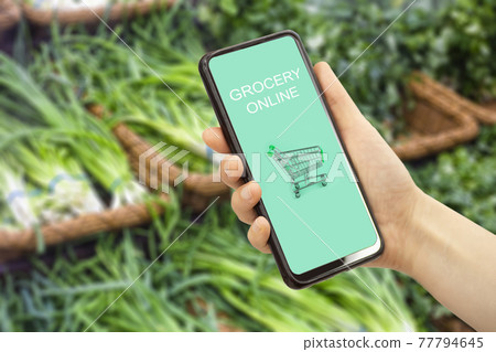 Online grocery delivery app in a mobile phone. Food market service in smartphone. Grocery delivery background concept. Shopping cart. Online grocery delivery app in a mobile phone. Food market service in smartphone. Grocery delivery background concept. Shopping cart. 77794645