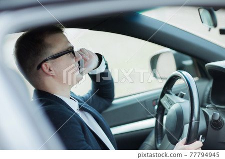 serious businessman talking on his smartphone while sitting in the car. serious businessman talking on his smartphone while sitting in the car. 77794945