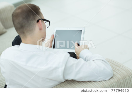 rear view. man reading text on digital tablet rear view. man reading text on digital tablet 77794950