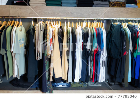 Interior of male clothing store with clothes on hangers and shelves Interior of male clothing store with clothes on hangers and shelves 77795040