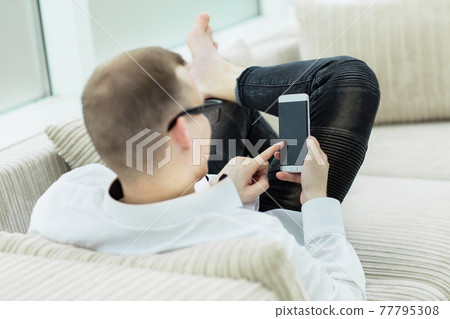 rear view.young man looking through a text on his smartphone rear view.young man looking through a text on his smartphone 77795308