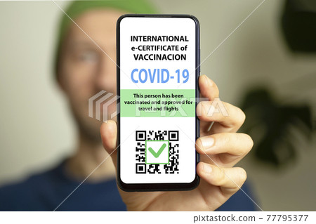 The men is holding a smartphone with electronic coronavirus vaccination certificate or vaccine passport for travellers. COVID-19 immunity e-passport mobile app for international travelling The men is holding a smartphone with electronic coronavirus vaccination certificate or vaccine passport for travellers. COVID-19 immunity e-passport mobile app for international travelling 77795377