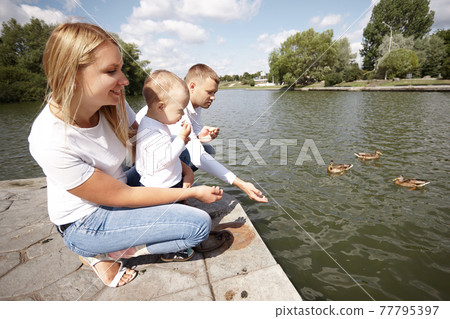 happy parents with their little son sitting on the lake pier 77795397