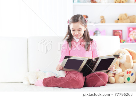 girl reading a book sitting on the couch in the nursery girl reading a book sitting on the couch in the nursery 77796263