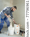 The worker mixes the solution in the bucket 77796961