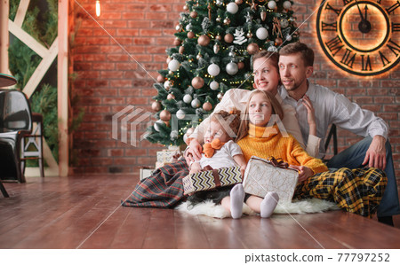 family with Christmas gifts in a cozy living room family with Christmas gifts in a cozy living room 77797252