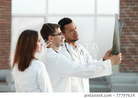 group of medical doctors discussing the patient's x-ray. 77797624