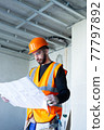 Male worker holding a paper apartment plan indoor before repair room  77797892