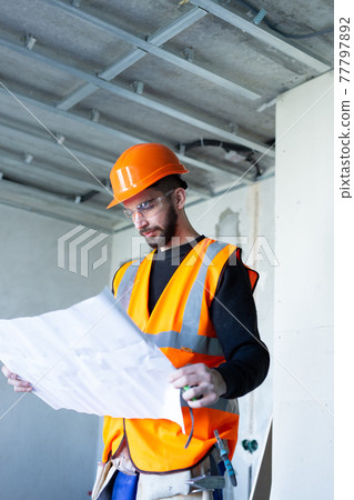 Male worker holding a paper apartment plan indoor before repair room Male worker holding a paper apartment plan indoor before repair room 77797892