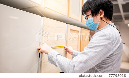Asian man using tape measure on cabinet material Asian man using tape measure on cabinet material 77798018