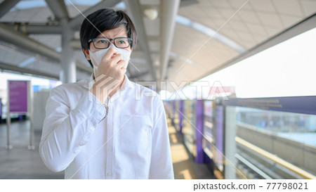 Asian man wearing mask at skytrain station Asian man wearing mask at skytrain station 77798021
