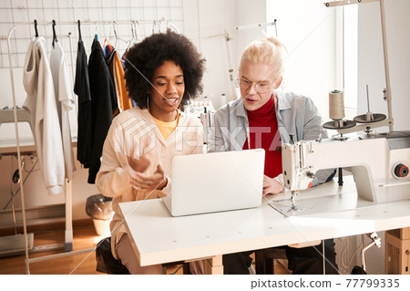Motivated designers sitting in front of the laptop and chatting with somebody Motivated designers sitting in front of the laptop and chatting with somebody 77799335