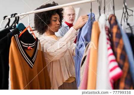 Woman showing shirt to her male albino colleague while advising Woman showing shirt to her male albino colleague while advising 77799338