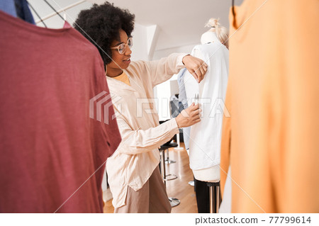 Woman adjusting shirt at the mannequin while engaged in the process of altering clothes Woman adjusting shirt at the mannequin while engaged in the process of altering clothes 77799614