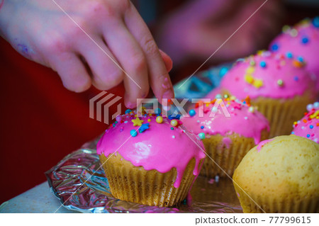 Freshly baked vanilla muffins are garnished with sweet icing and topping. Freshly baked vanilla muffins are garnished with sweet icing and topping. 77799615