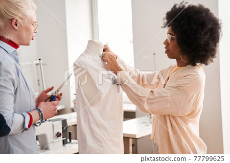 Woman adjusting shirt at the mannequin while re sewing clothes Woman adjusting shirt at the mannequin while re sewing clothes 77799625