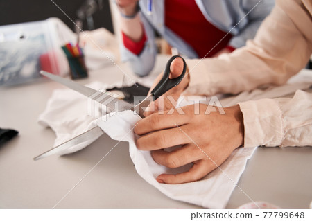 Man and woman colleagues cutting t shirt with scissors while creating something great Man and woman colleagues cutting t shirt with scissors while creating something great 77799648
