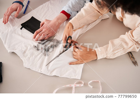 Man and woman colleagues cutting t shirt with scissors while creating something great 77799650
