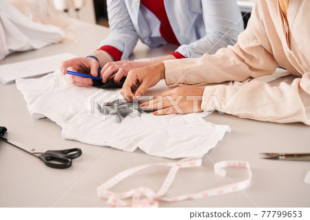 Colleagues applying fabric samples to the clothing while giving new life to the clothes 77799653