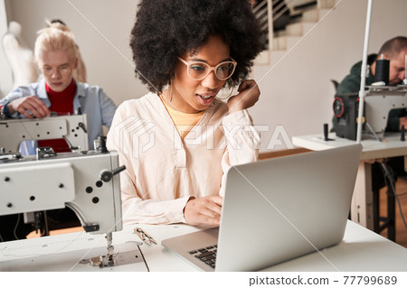 Woman sitting in front of the laptop and chatting with colleagues remotely Woman sitting in front of the laptop and chatting with colleagues remotely 77799689