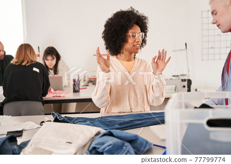 Woman discussing process of re sewing with her albino colleague while working Woman discussing process of re sewing with her albino colleague while working 77799774