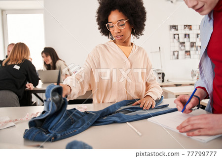 Woman discussing process of re sewing with her albino colleague while working Woman discussing process of re sewing with her albino colleague while working 77799777
