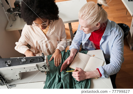 Designer drawing new sketches and telling something to his multiracial colleague Designer drawing new sketches and telling something to his multiracial colleague 77799827