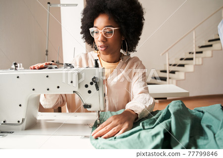 Woman recycling clothes and re sewing it for environmental purposes Woman recycling clothes and re sewing it for environmental purposes 77799846