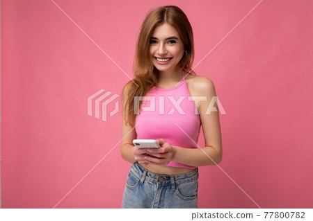 Photo of good looking smiling young blonde woman wearing pink top poising isolated on pink Photo of good looking smiling young blonde woman wearing pink top poising isolated on pink 77800782