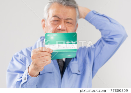 Senior man in work clothes looking at passbook Senior man in work clothes looking at passbook 77800809