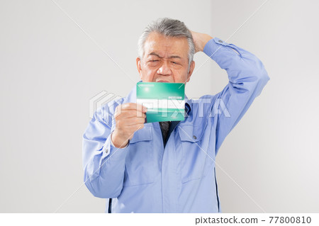 Senior man in work clothes looking at passbook 77800810