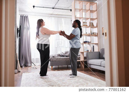 Couple in love smiling to each other and holding hands while dancing 77801162