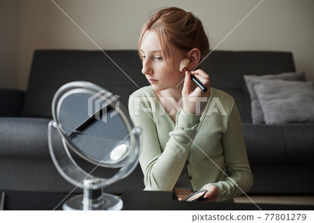 Freckled girl sitting in front of the mirror and preparing makeup 77801279