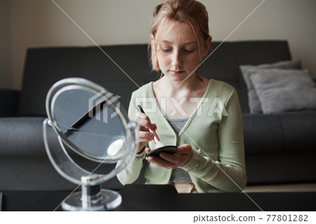 Girl sitting in front of the mirror and preparing makeup 77801282