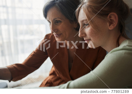 Woman and her granddaughter looking at the mirror at the results of the makeup 77801289