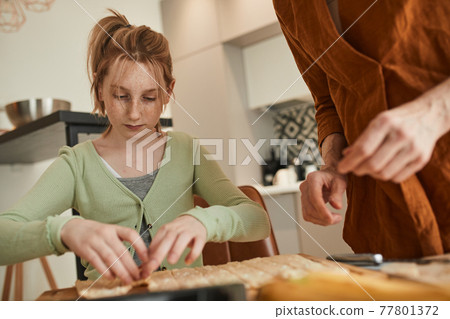Girl preparing bagels from the dough while helping to her senior grandmother 77801372
