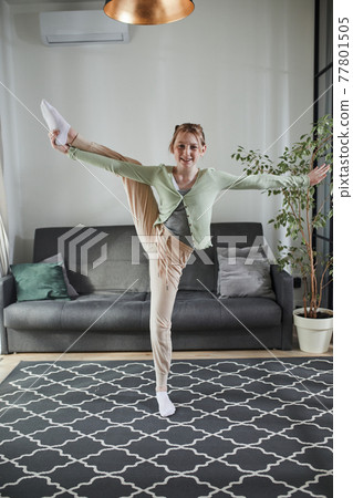 Girl standing at the one leg and practicing gymnastics at home at the morning 77801505