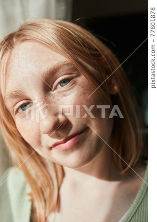 Girl looking at the camera while sitting at the windowsill and enjoying of the good day 77801878