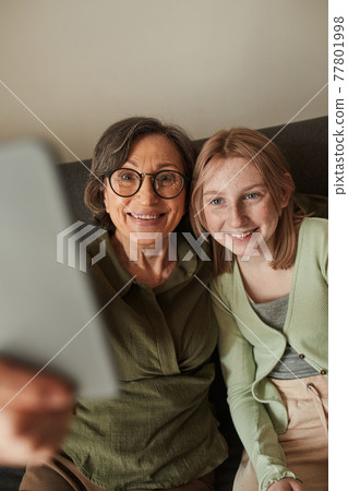 Freckled girl bonding to her senior grandmother while making selfie together Freckled girl bonding to her senior grandmother while making selfie together 77801998
