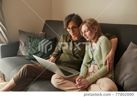 Grandmother embracing her granddaughter while watching interesting movie Grandmother embracing her granddaughter while watching interesting movie 77802000