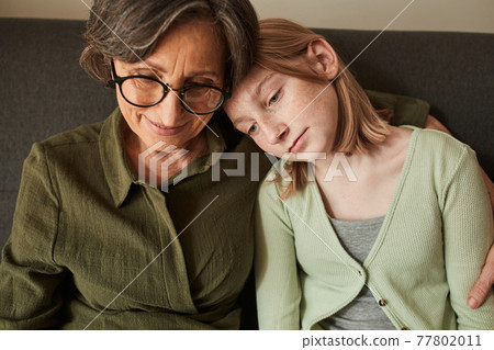 Girl bonding to her senior grandmother and watching something at the laptop 77802011