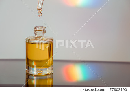 Face oil on reflective surface with a rainbow streak 77802190
