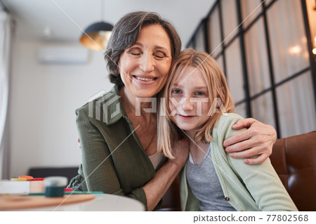 Grandmother closed eyes with pleasure and embracing her granddaughter Grandmother closed eyes with pleasure and embracing her granddaughter 77802568