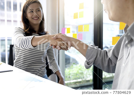 Two business people are shaking hands to congratulate Two business people are shaking hands to congratulate 77804629