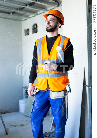 Male worker holding a paper apartment plan indoor before repair room Male worker holding a paper apartment plan indoor before repair room 77804679