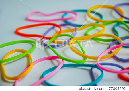 Side view of colorful rubber bands on white. Rainbow elastic rubber bands on white. Selective focus. Side view of colorful rubber bands on white. Rainbow elastic rubber bands on white. Selective focus. 77805392