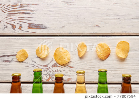 Chips above beer bottlenecks, wooden background. Chips above beer bottlenecks, wooden background. 77807594