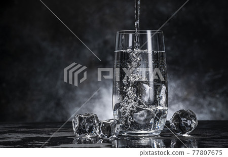 Pouring water from bottle into glass on black background Pouring water from bottle into glass on black background 77807675
