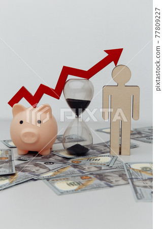 Piggy bank, hourglass and wooden person with arrow up on dollar banknotes close-up. Investment and time concept. Vertical image 77809227