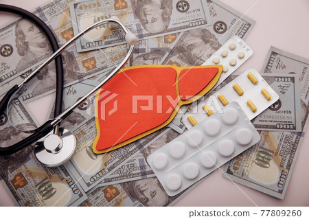 Model of liver lies on banknotes of dollar banknotes close-up, concept of treatment and healthcare 77809260